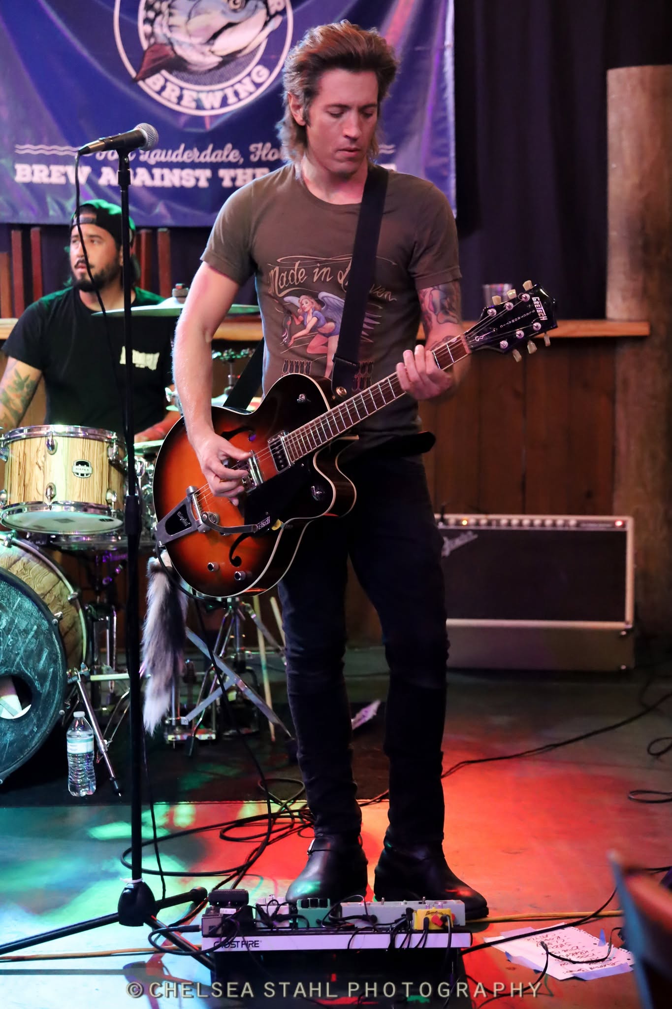 A Shakers guitarist performing under colorful stage lights