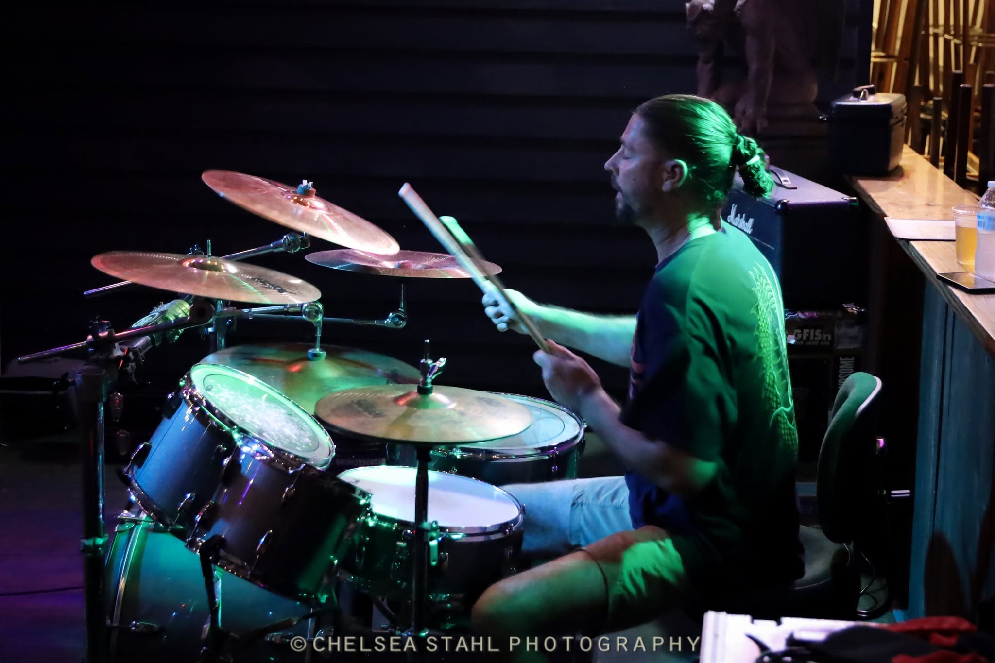 Side view of the Shakers drummer under green stage lights