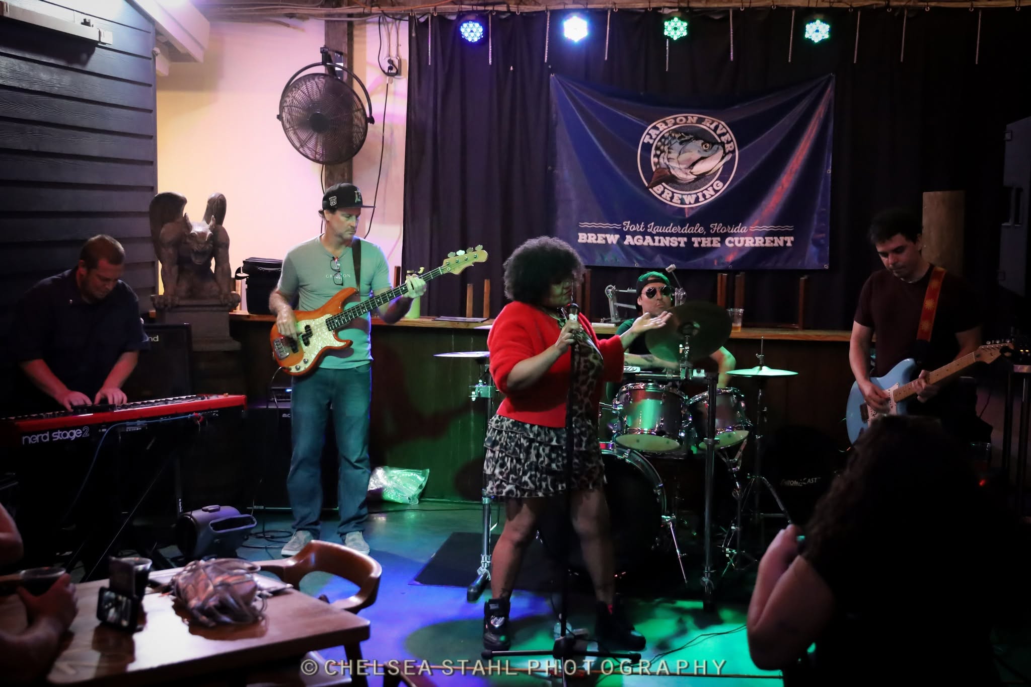 Full band performing under the Tarpon River Brewing stage lights